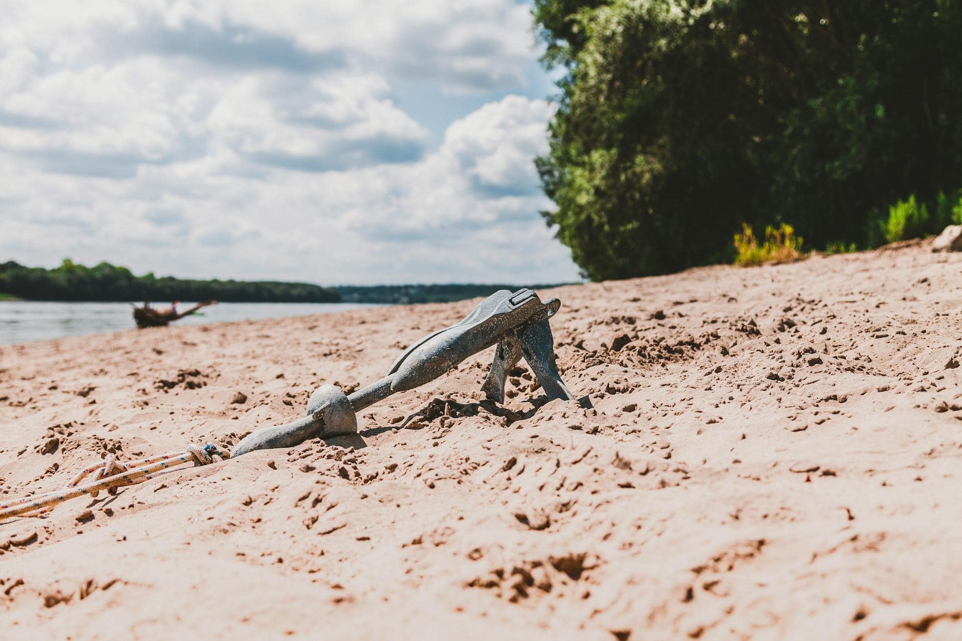 Grey boat grapple anchor in the sane with rope attached. 