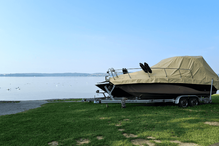 Powerboat covered and on trailer at lakeside marina, showcasing boat maintenance and storage solutions for boat owners, with a focus on boat care, repair, and yacht maintenance services.