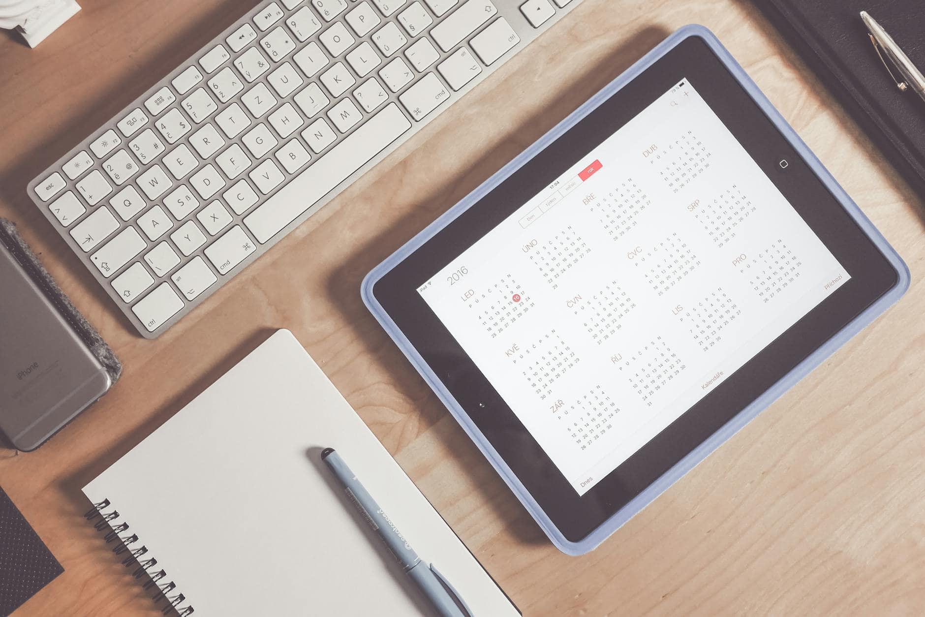 grey apple keyboard and grey ipad with a calender page open on screen