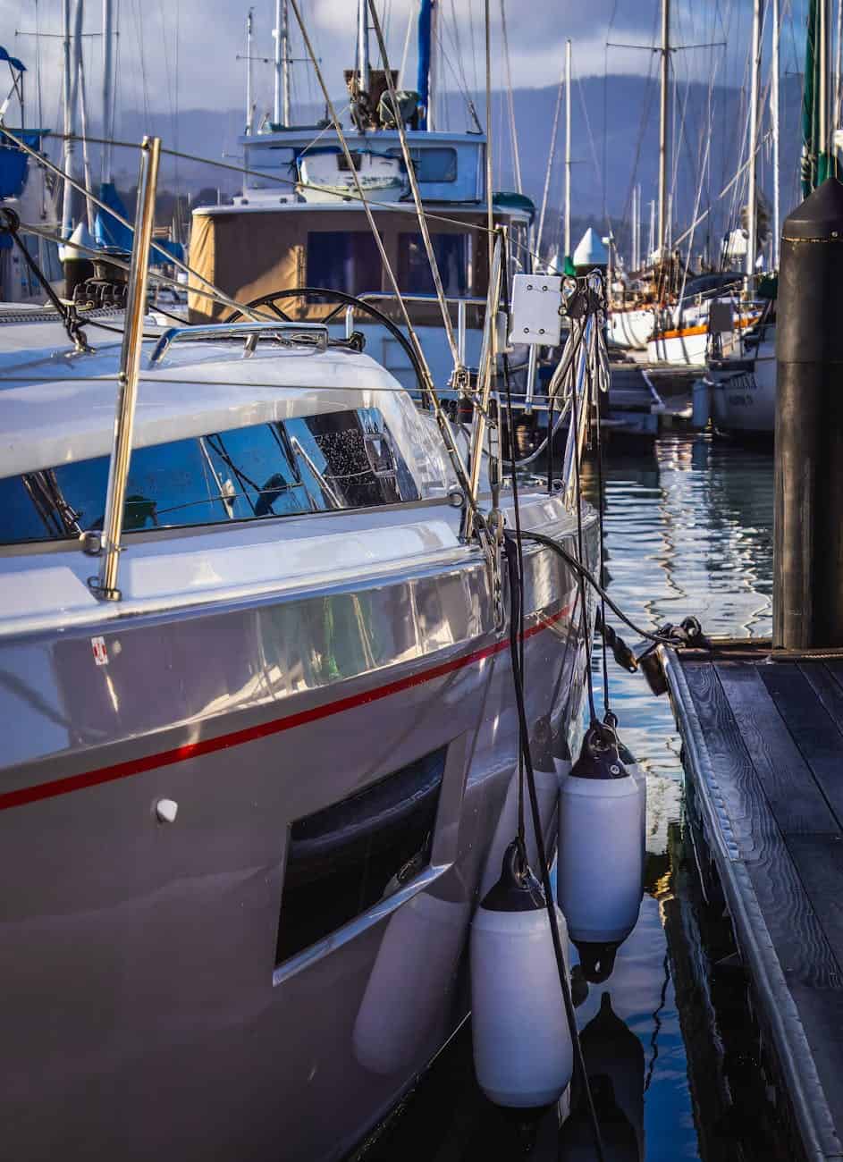 grey yacht paint shining in a marina with red stripe through the middle. 