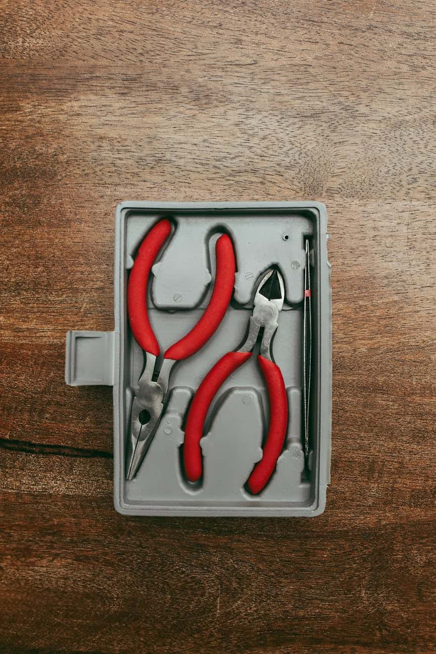 red pliers in a box on wooden background 