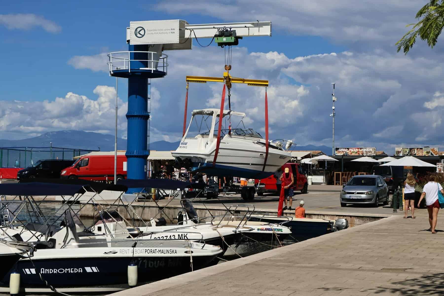 boat being lifted at a busy marina undergoing a maintenance schedule. 