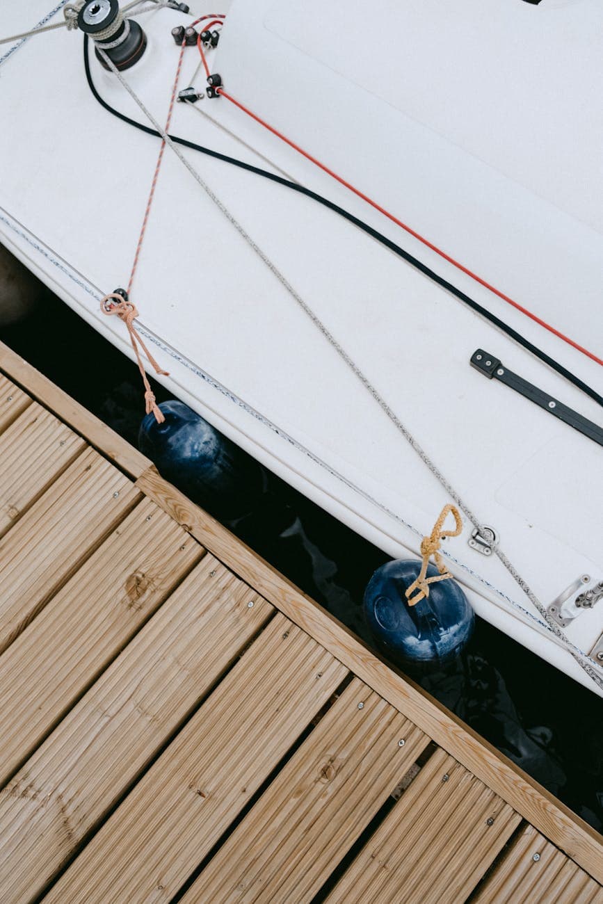 Blue fenders hanging off a yacht railing touching a wooden dock. 