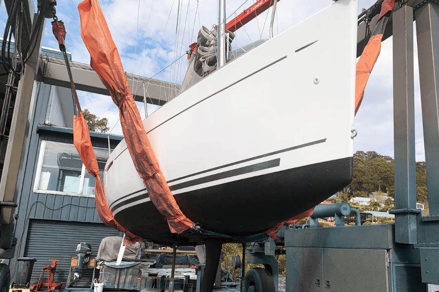 Sailing yacht being put back into the water. Fresh black antifouling applied. 