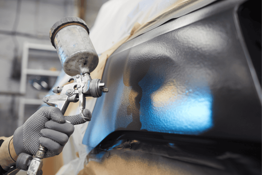 Paint being sprayed onto surface in black. Showing marine paint application. 