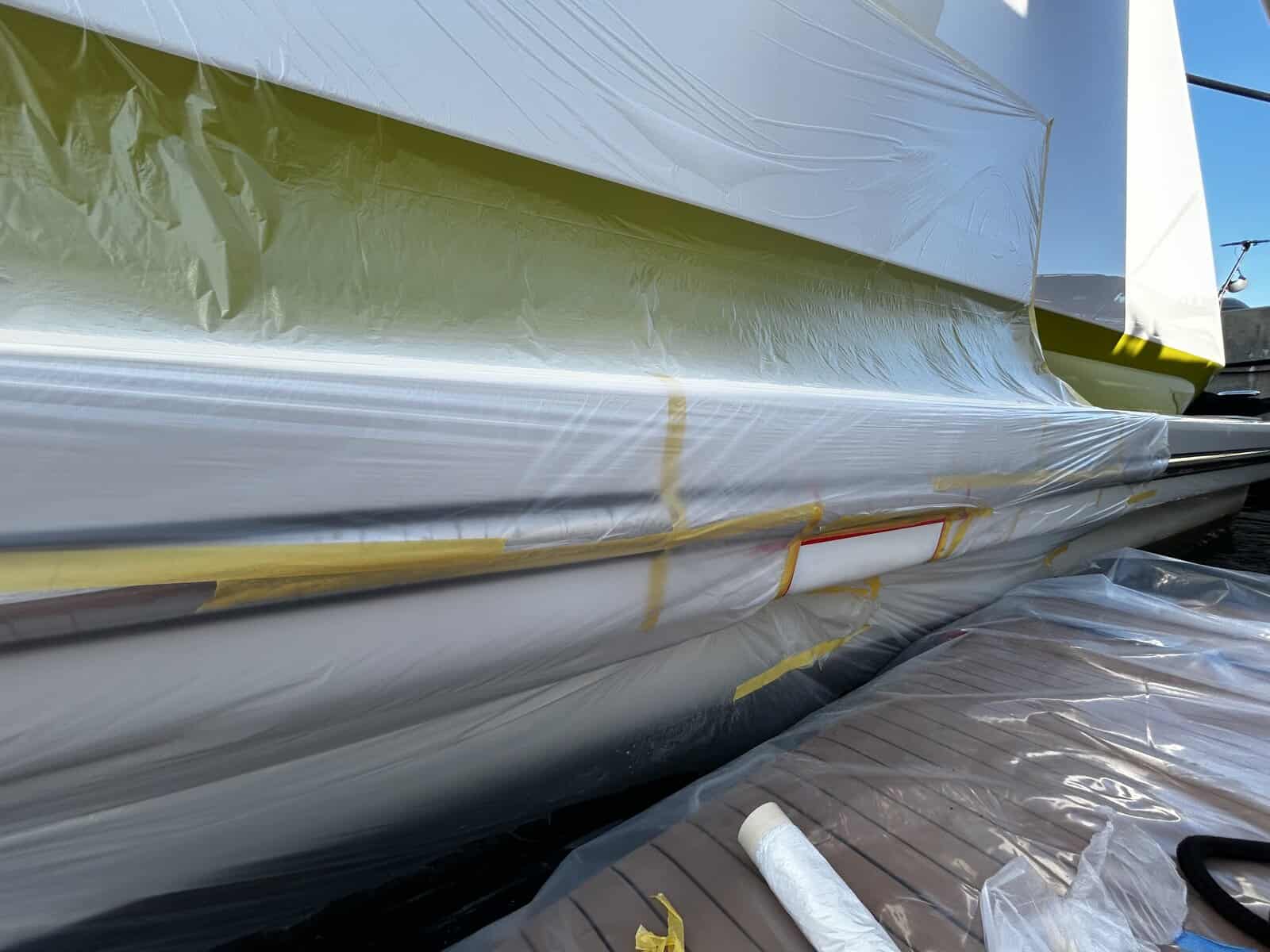 Yacht paint application in progress with tenting on a yachts hull. 