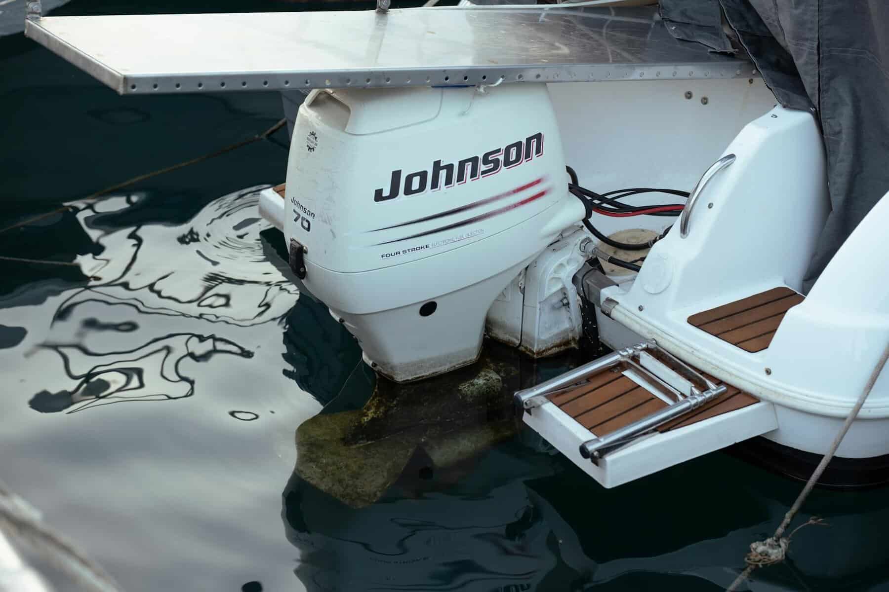 Close up of boat with a white Johnson outboard motor with algae and growth around the prop.