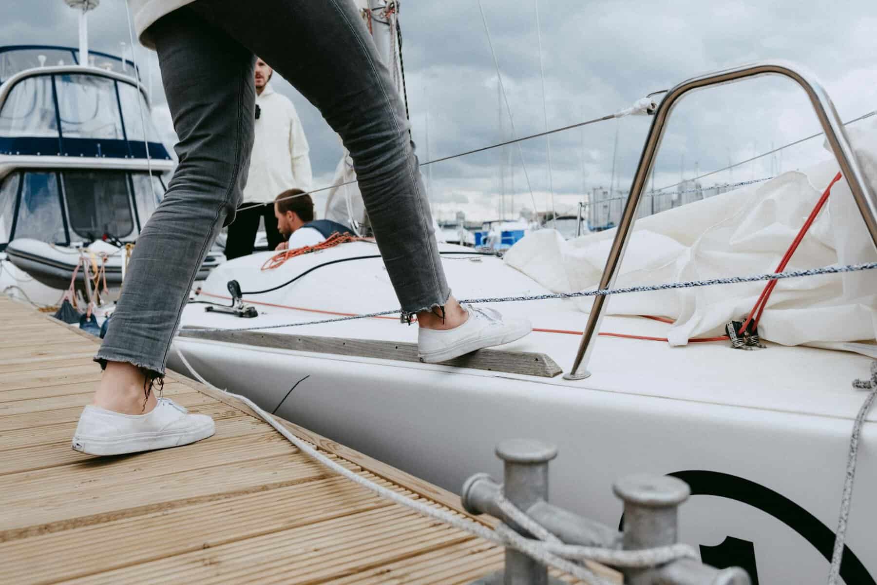 person in gray pants and black socks standing on white boat stepping onto non skid paint. 