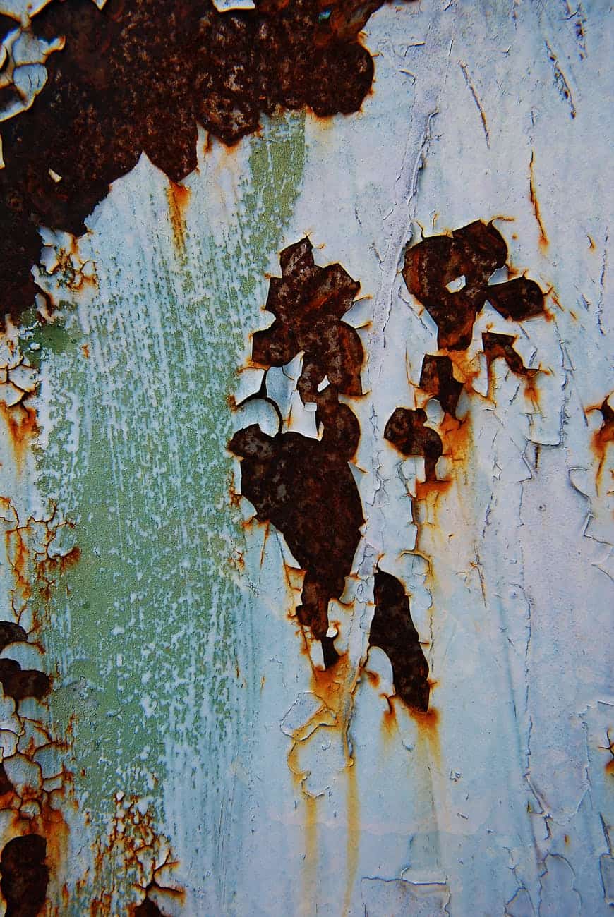 Rust stains on a painted surface cracking through. 