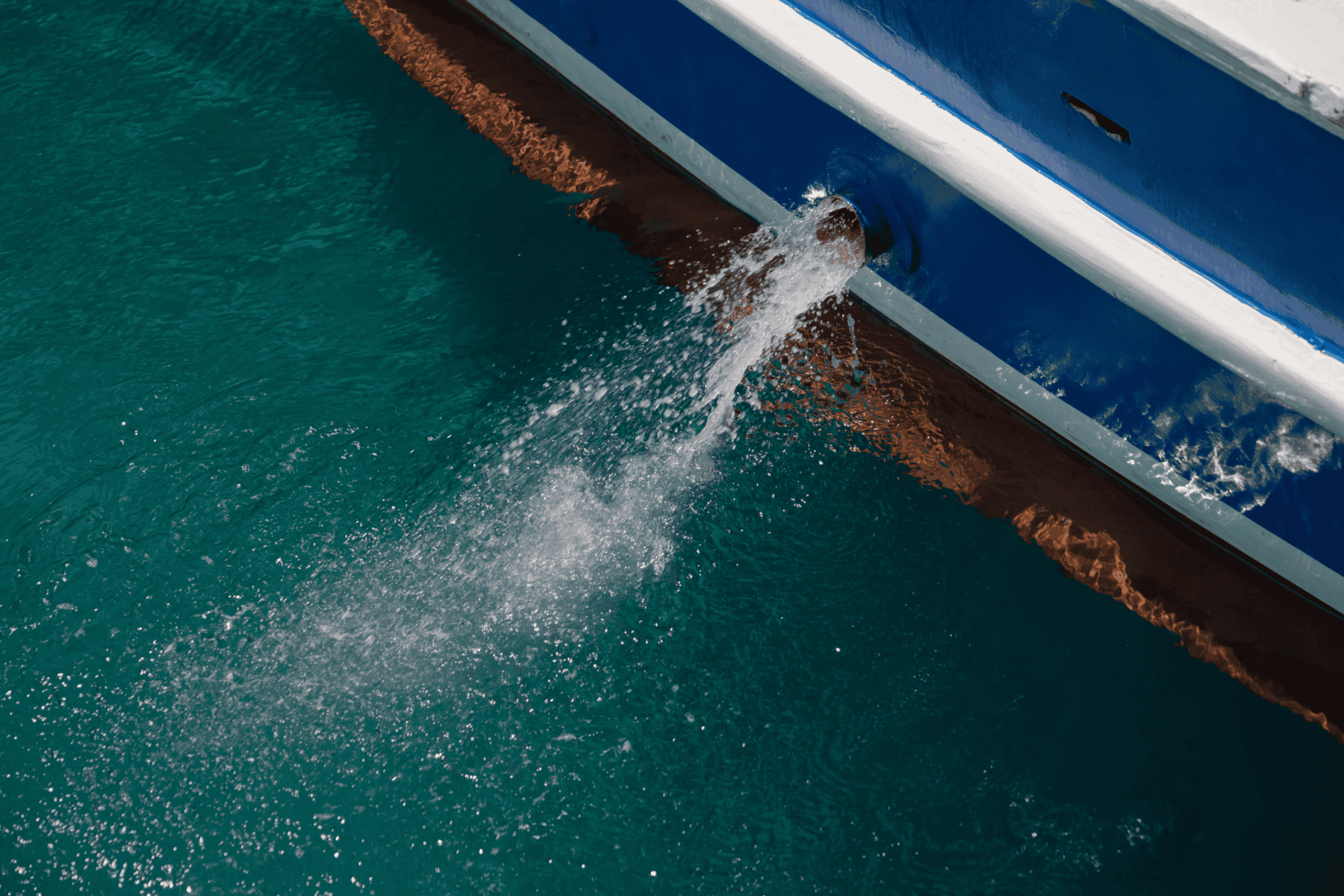 Through hull fitting on a boat with water being pumped out overboard.