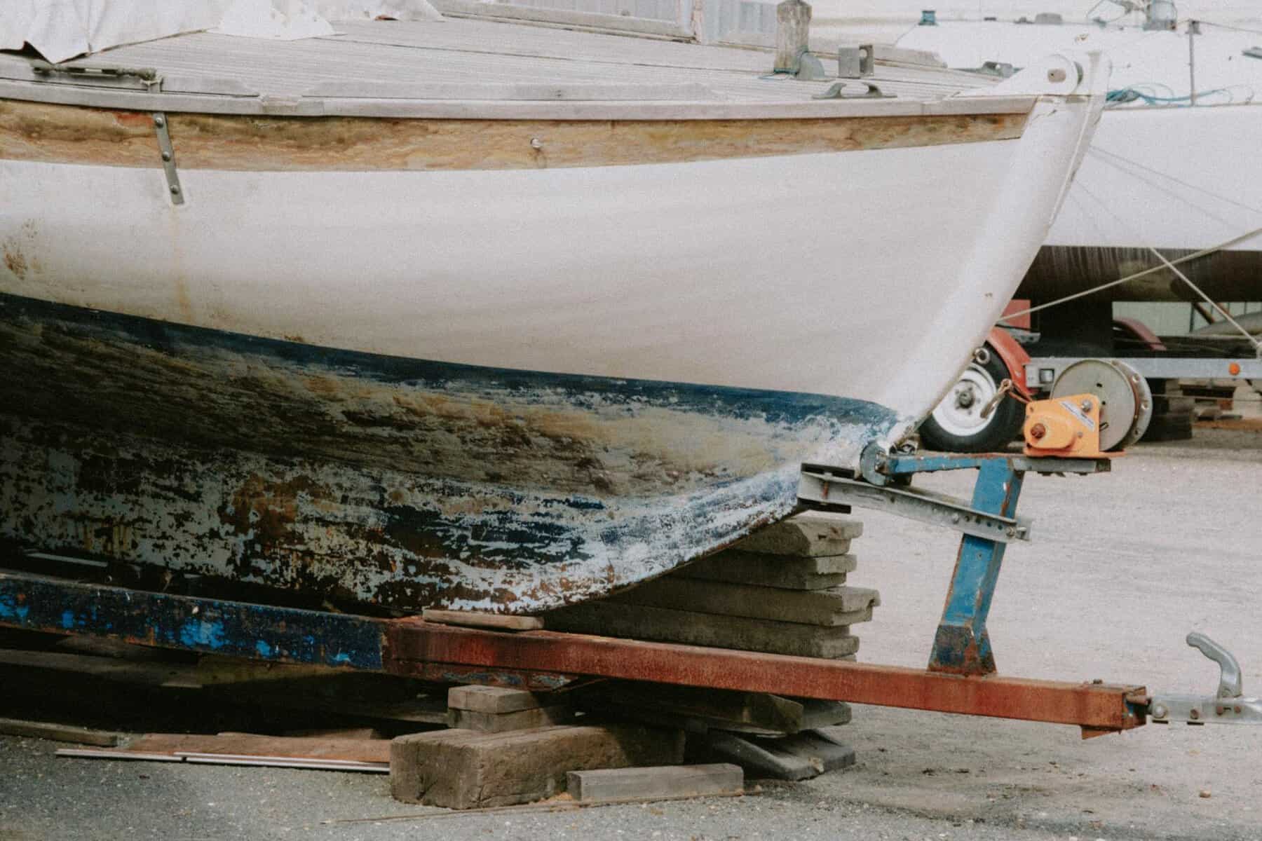 damaged boat on a trailer with a dirty hull