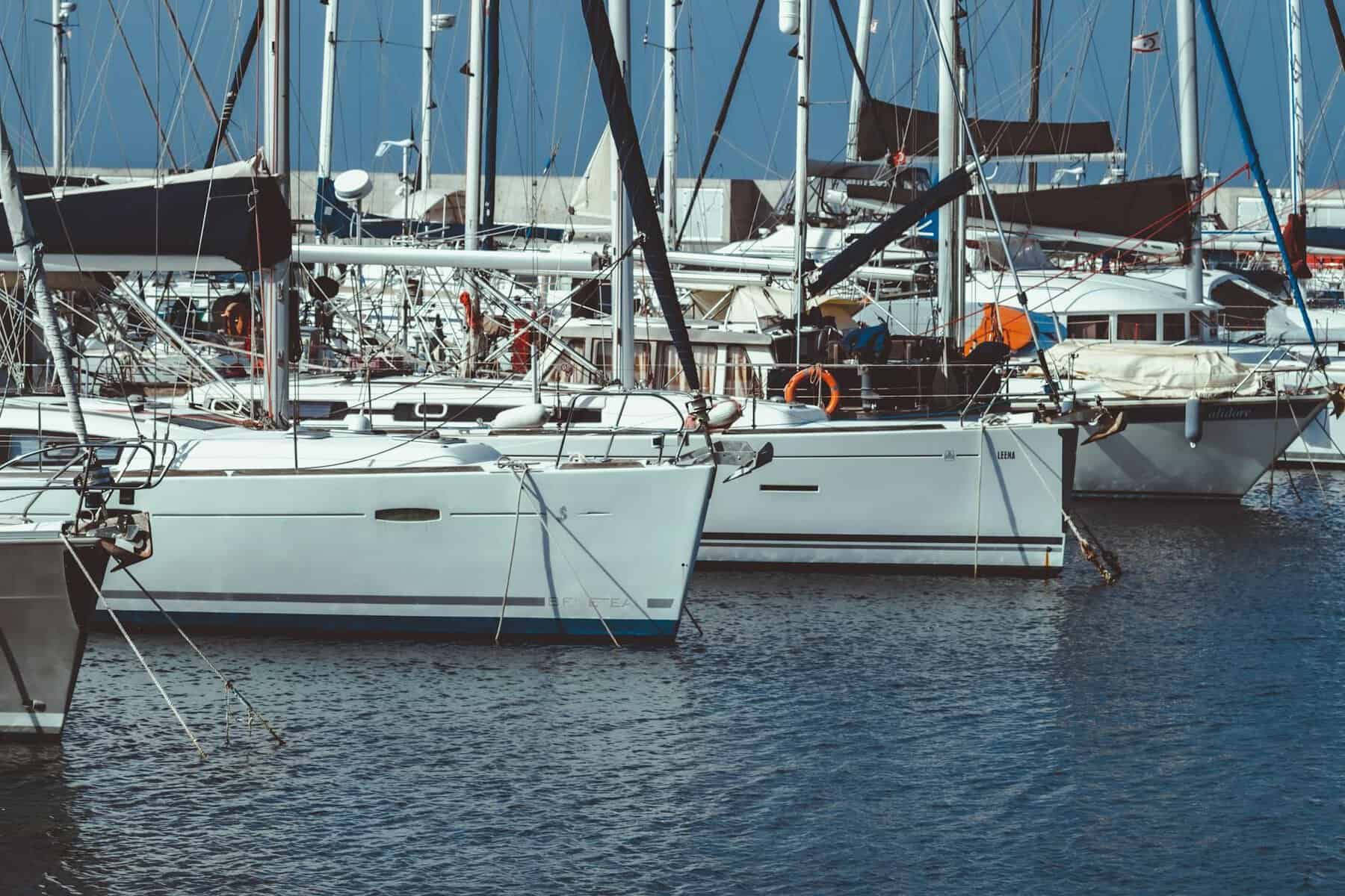 sailboats moored in marina with clean hulls. Some showing signs of needing oxidation removal. 