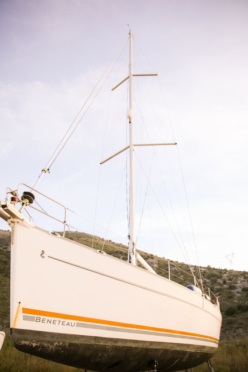 A white beneteau sailing yacht with orange boot stripe. Being heled up on blocks out of the water. 