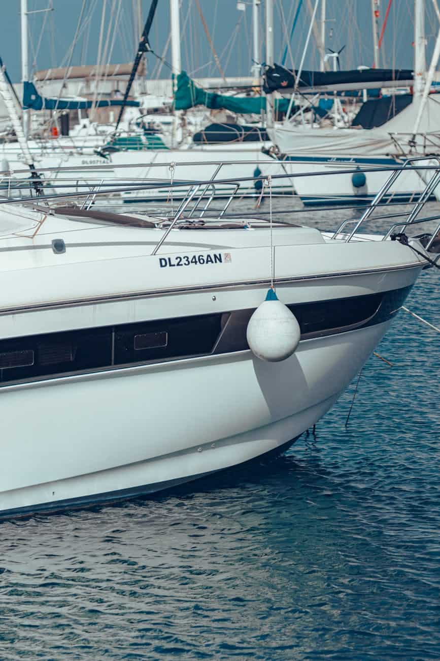 a white boat docked at a marina with a fender over the side of the hull. 