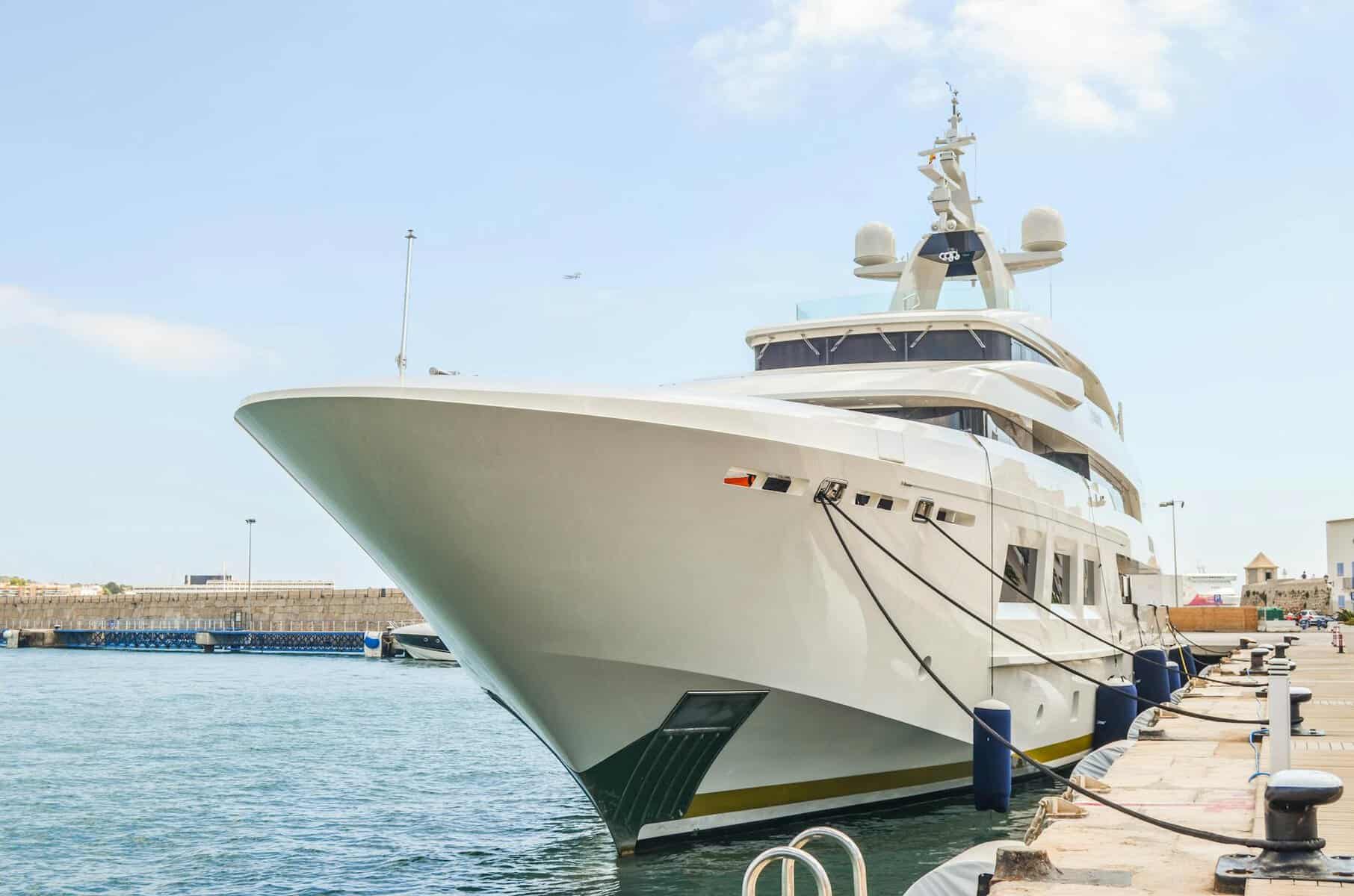 a large white yacht docked at a dock. showing a clean yacht hull from the bow aspect. 