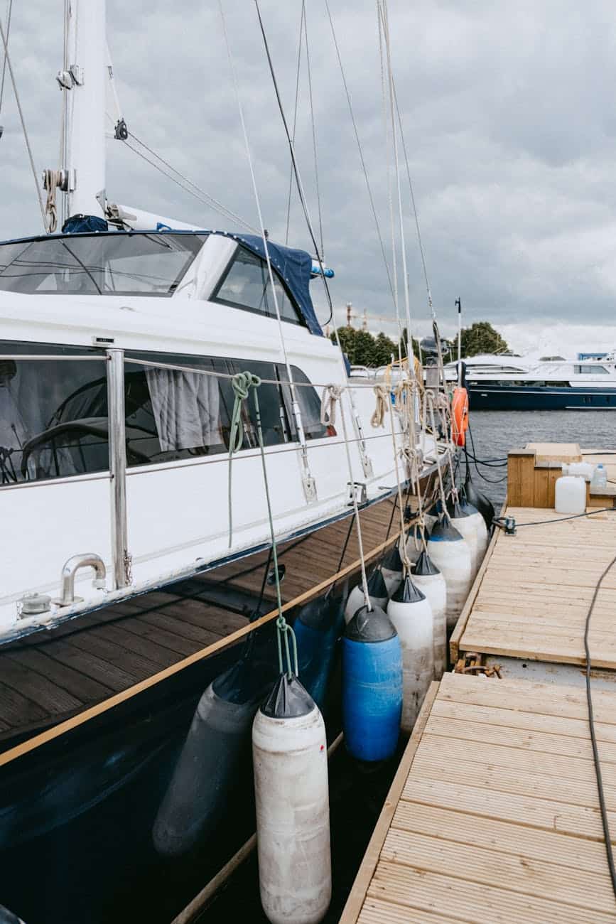 White yacht with blue hull on the dock with fenders protecting the paint. 