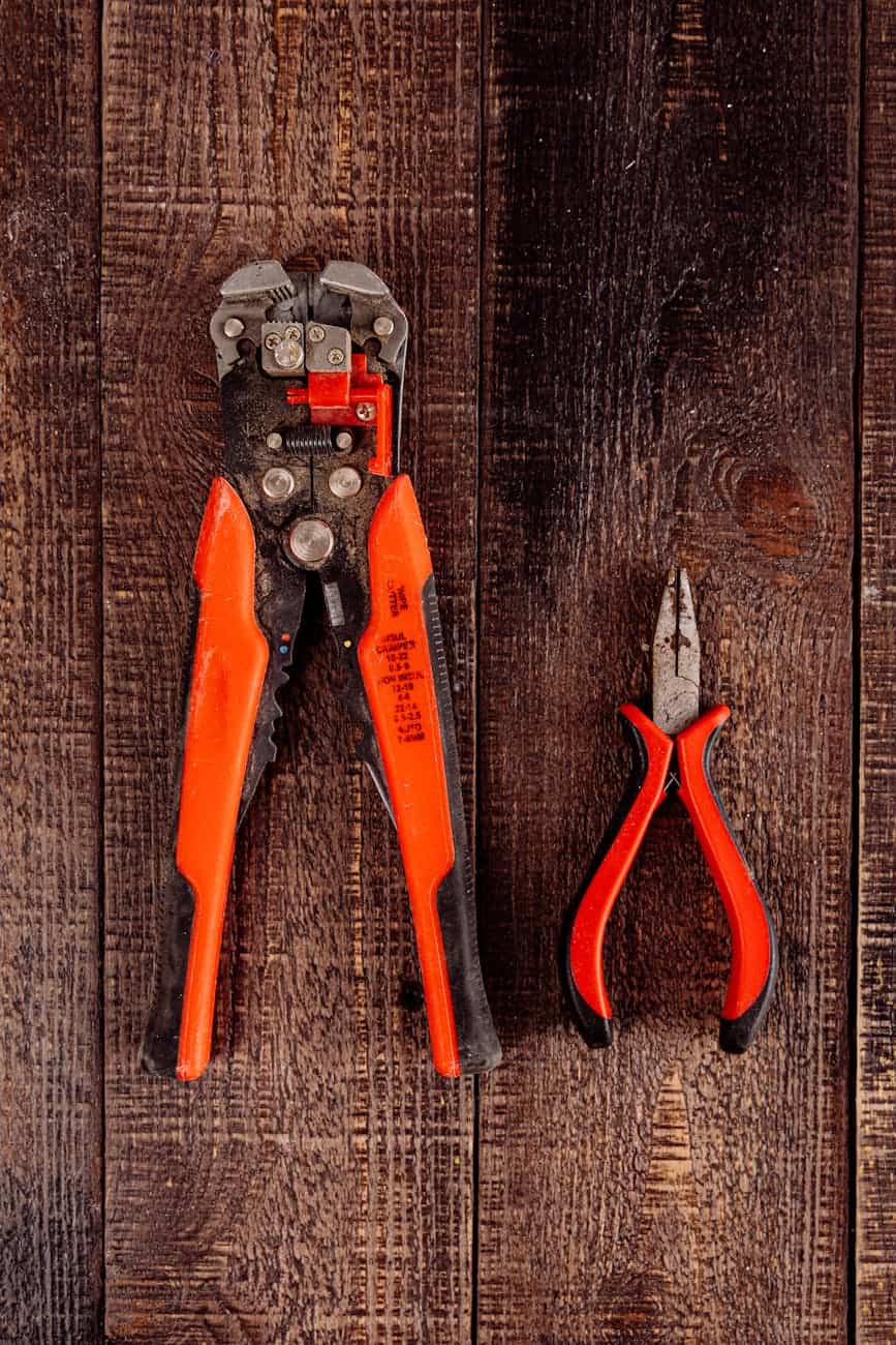 Red wire strippers on wooden bench 