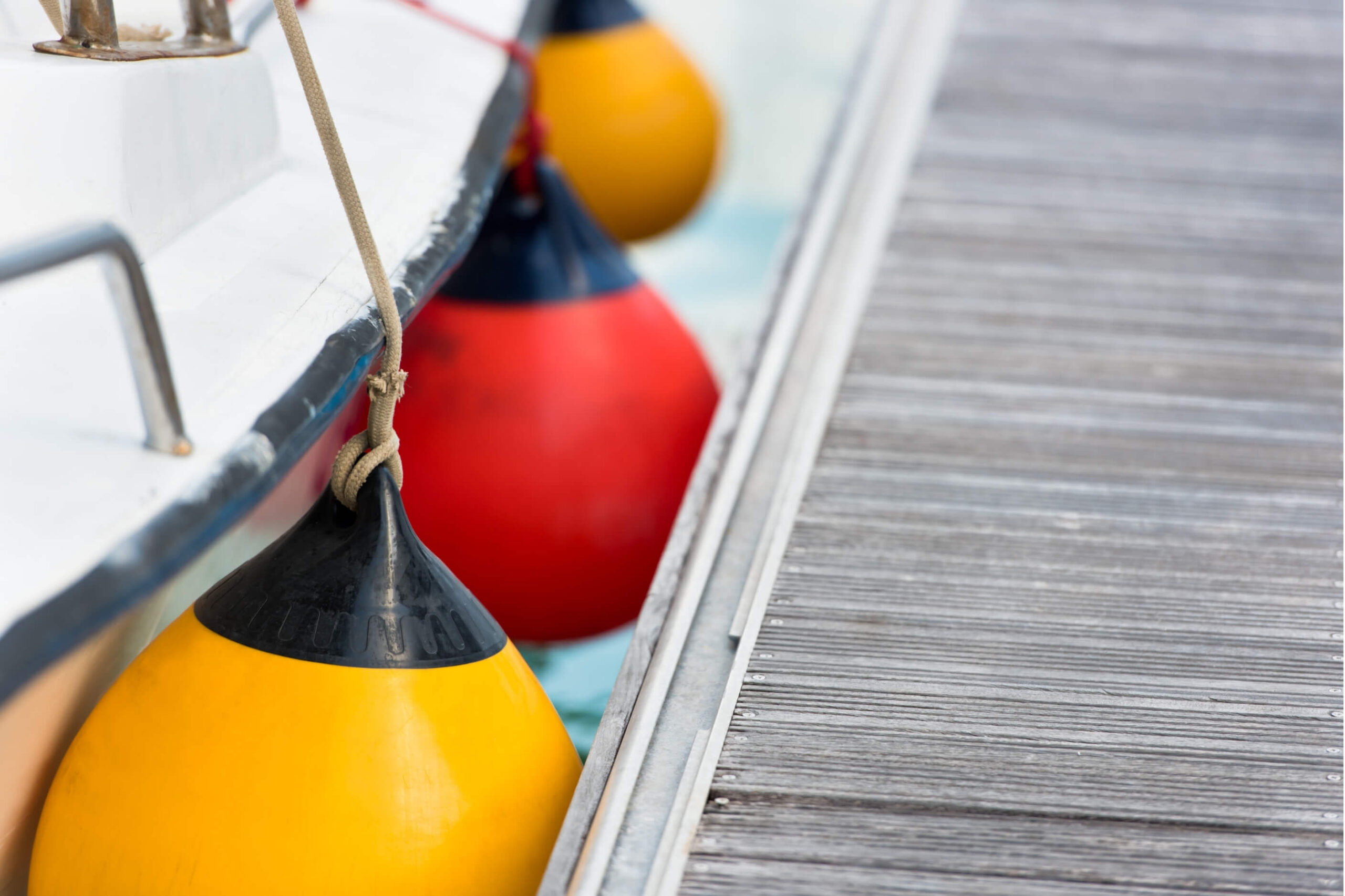 Red and Yellow fenders protecting a yacht from hitting the wooden dock. 