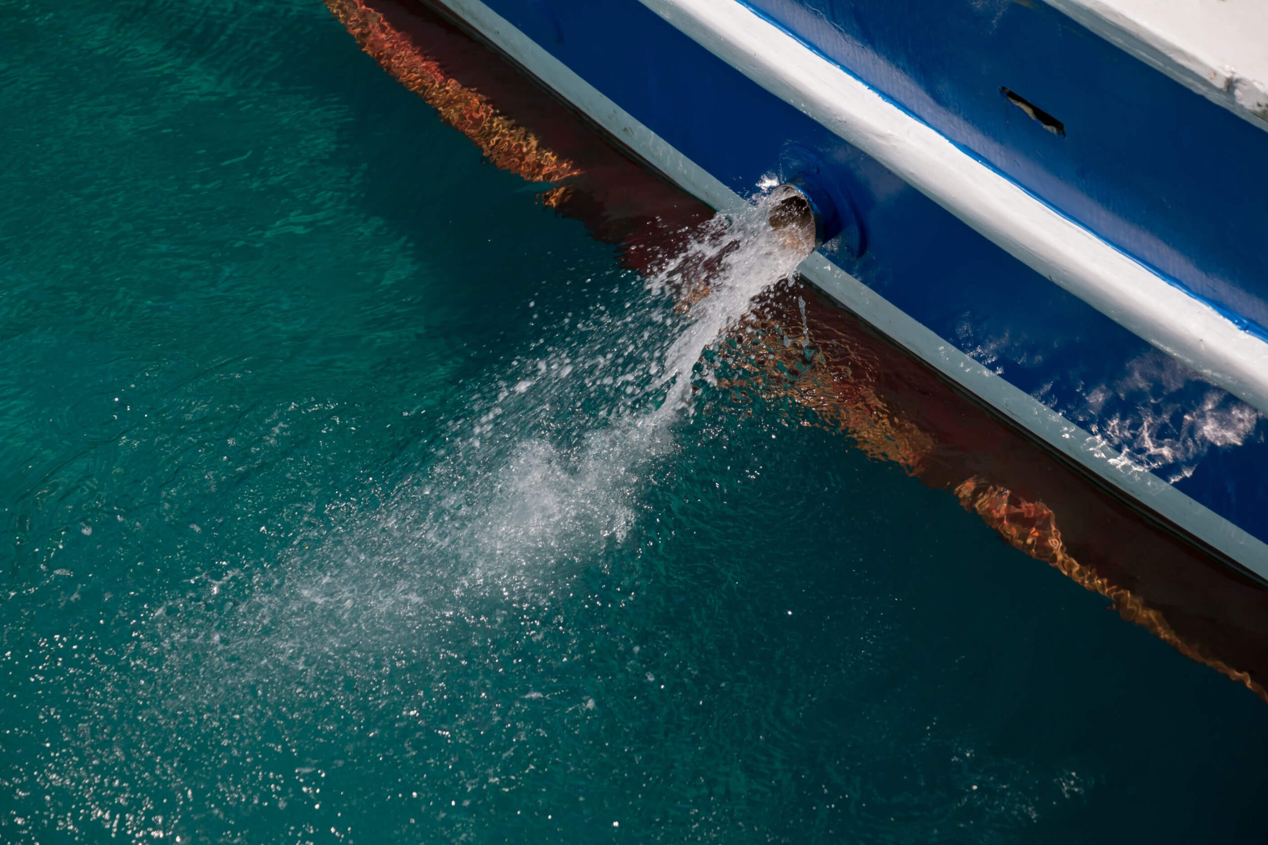 Water coming out of through hull fitting in the side of a yacht. 