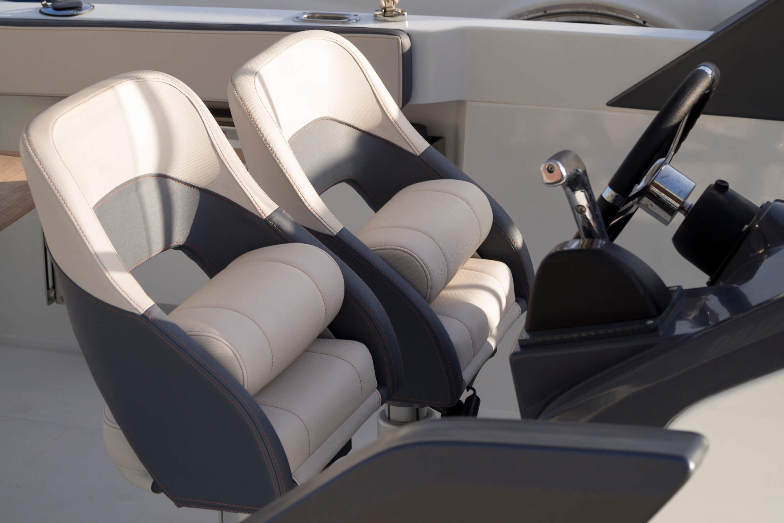 Cream & grey boat seats in the cockpit of a single engine power boat. 