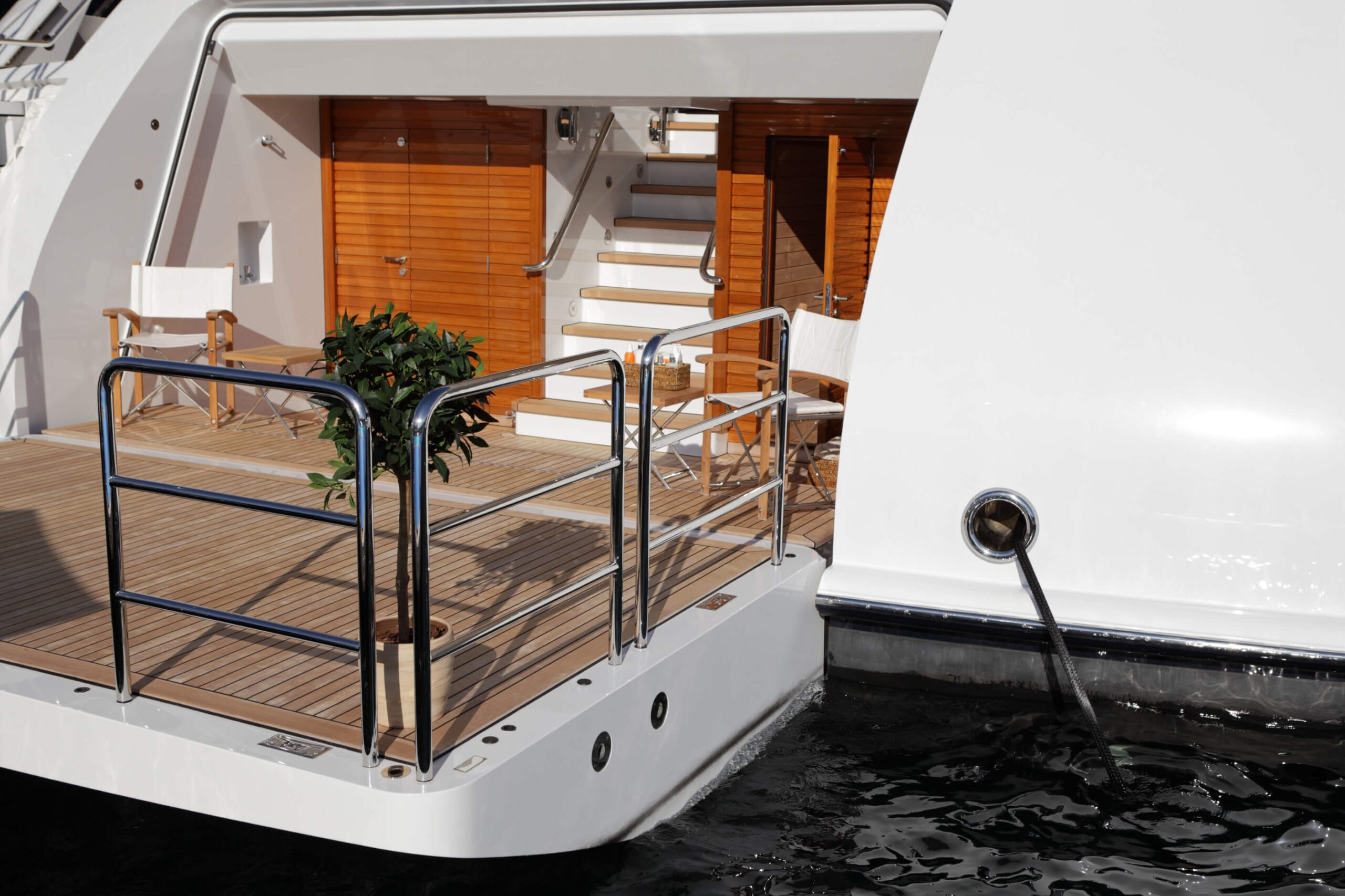 Superyacht transom down with a teak deck and guest chairs. 
