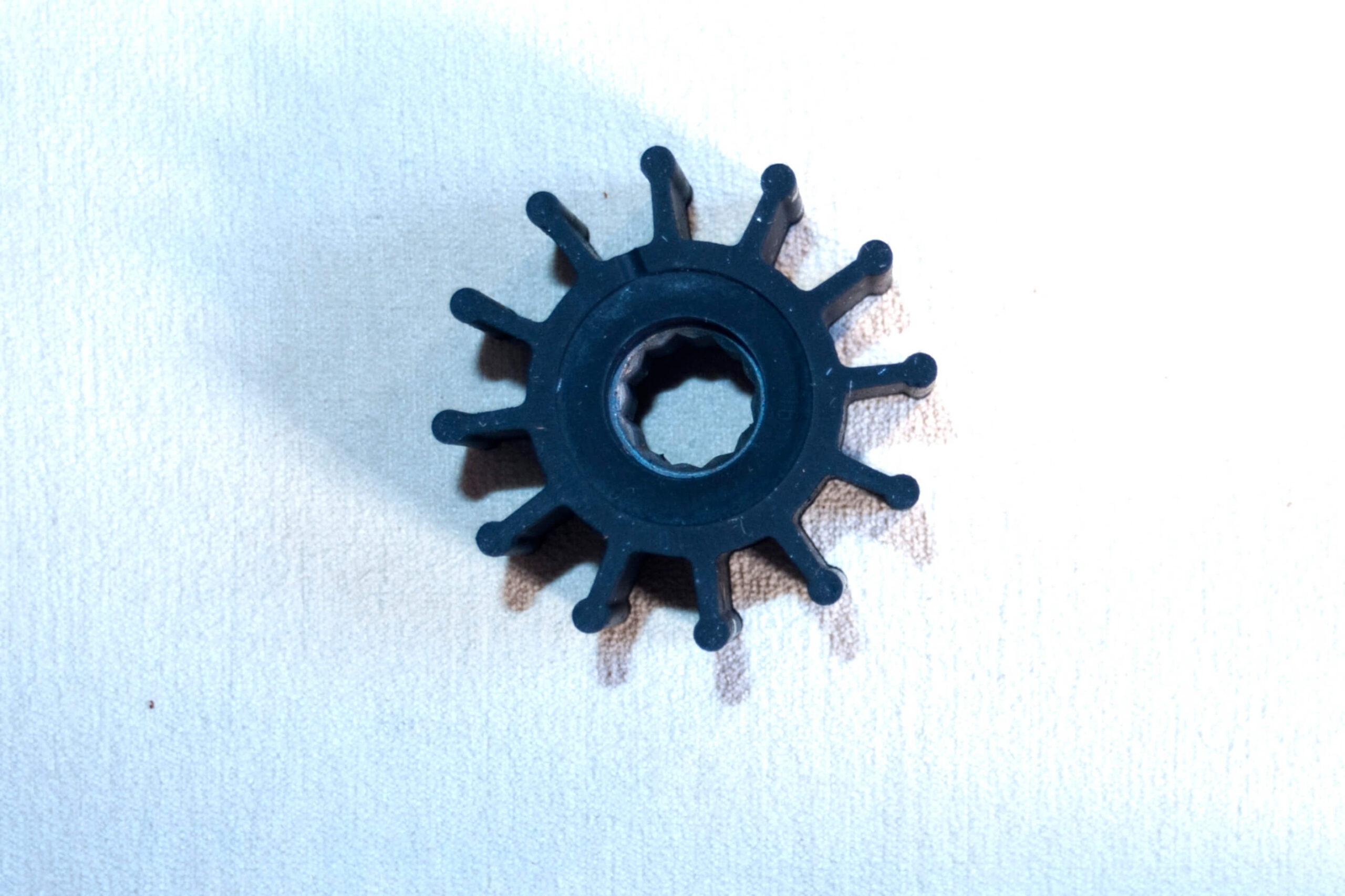 Black raw water pump impeller on a white background.