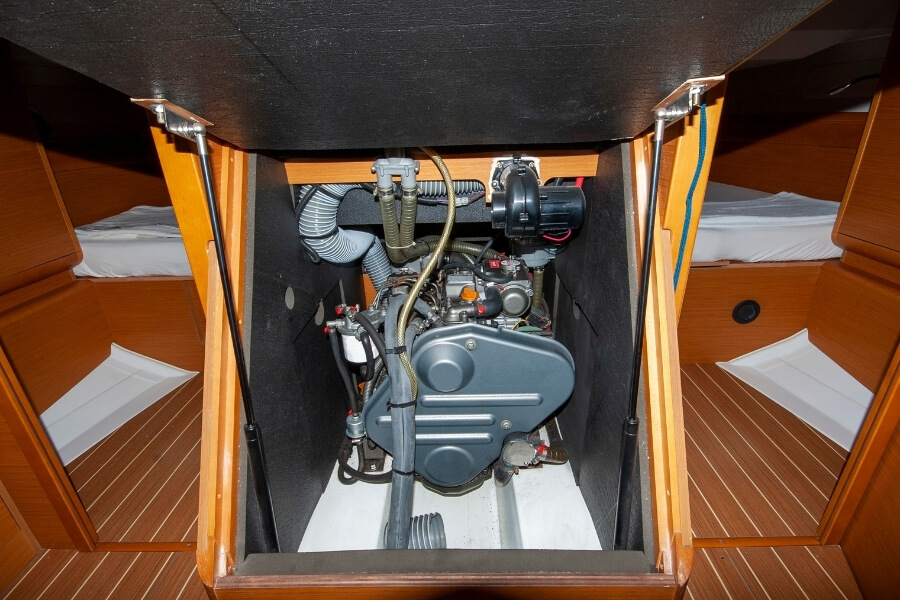 Marine diesel engine underneath the stairs of a sailing yacht with a teak interior. 