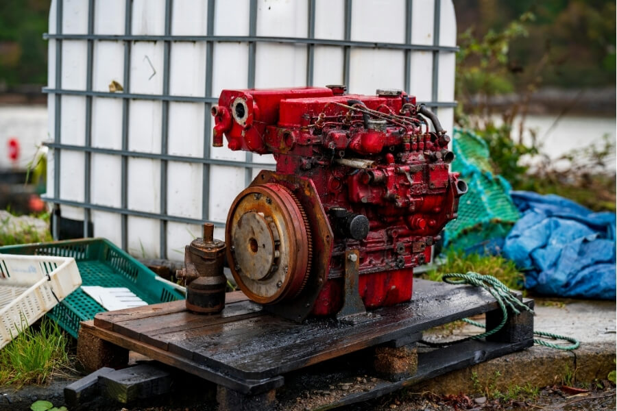 Old red marine diesel engine on a wooden pallet. 
