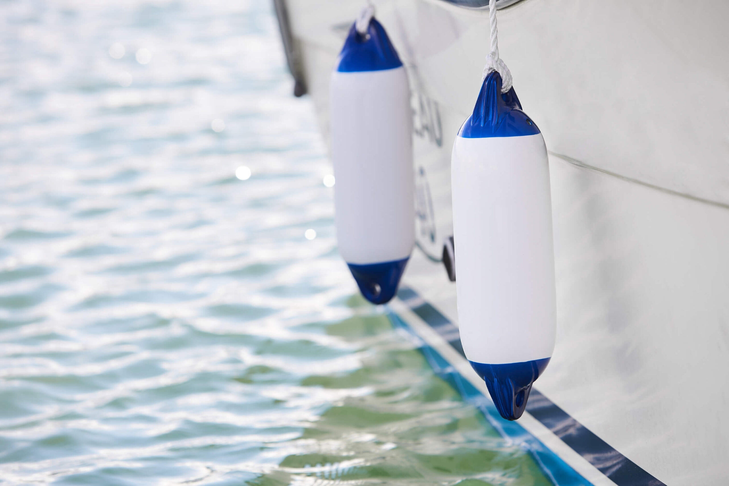 Clean boat fenders hanging offa yacht hull. 