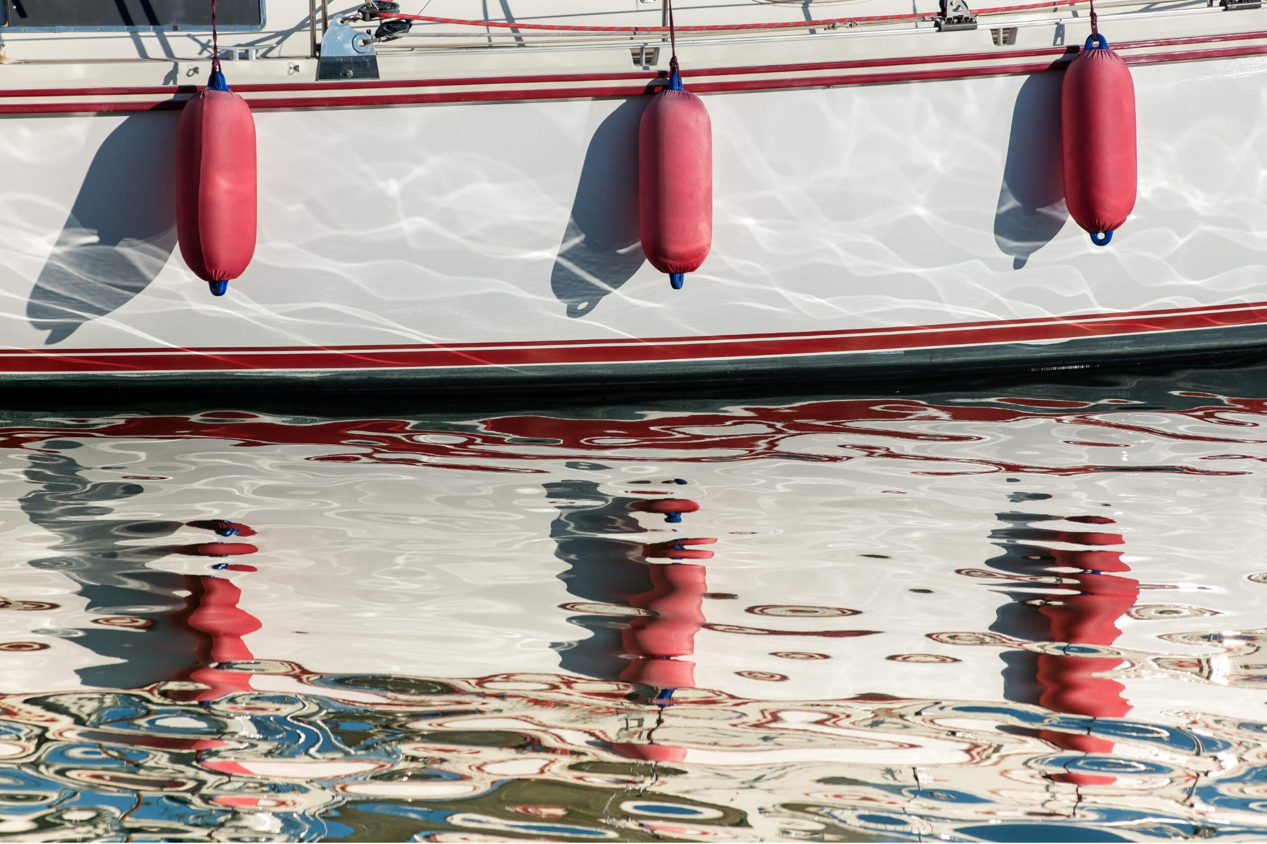 Clean boat fenders a white hull with red fender covers and red lines through the hull.