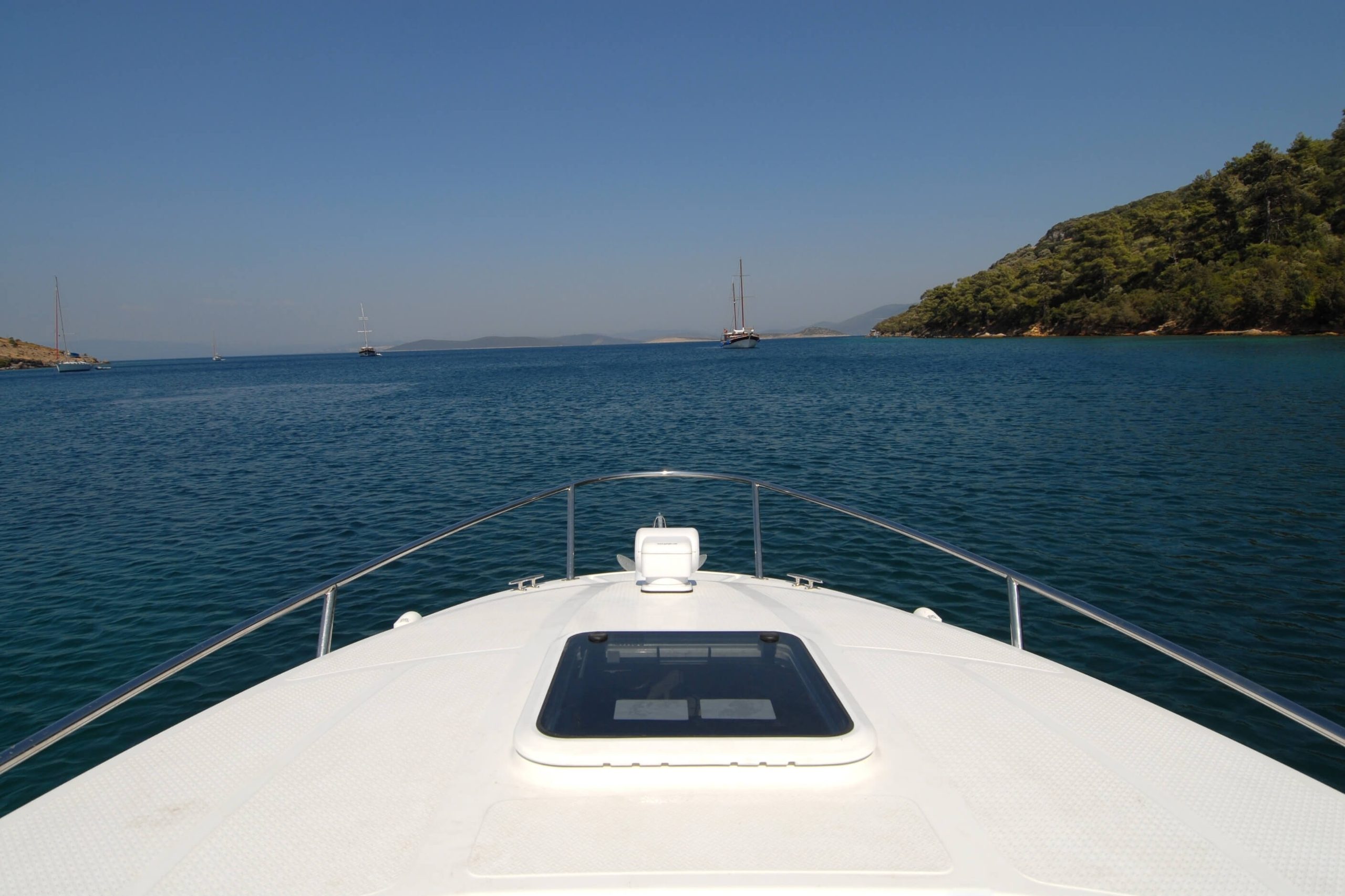 Clean boat deck on the bow of a power boat looking over a sunny bay. 