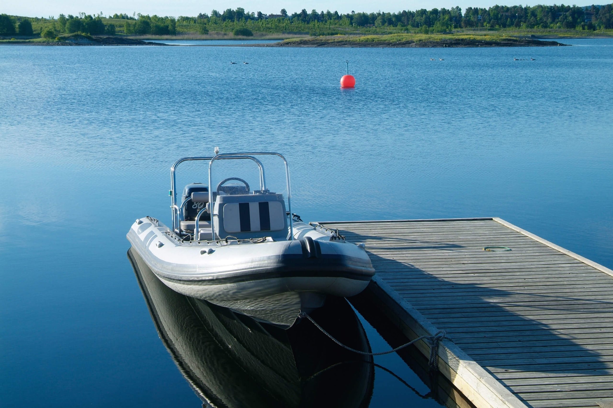 Grey clean inflatable boat on the water tied to the dock. 