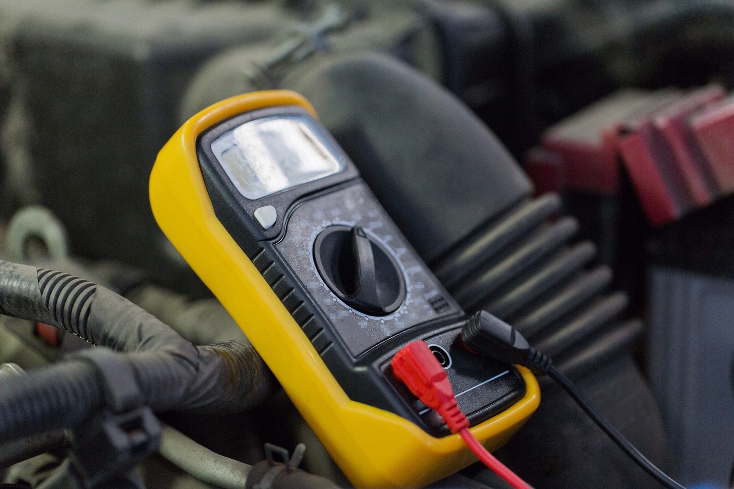 yellow and black multimeter testing a  boat battery. 